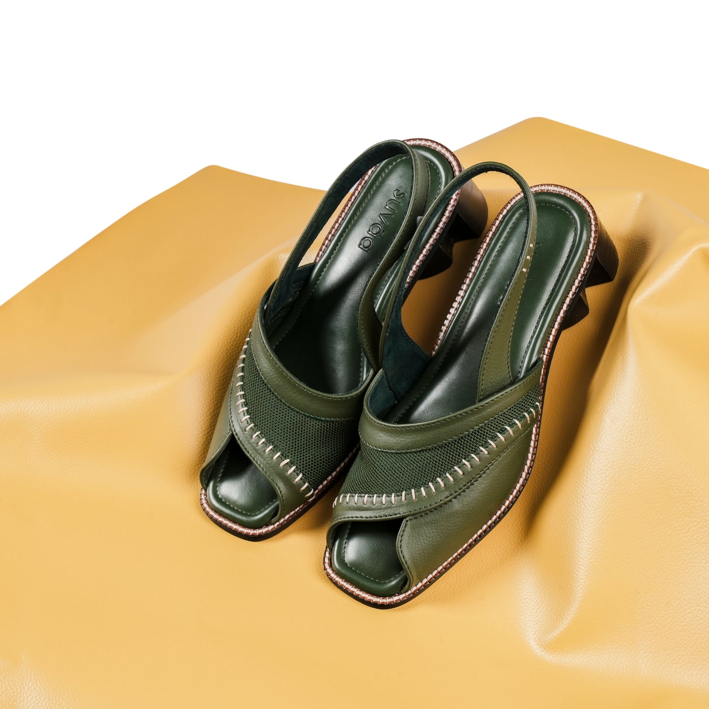 Green open-toe shoes on a beige surface