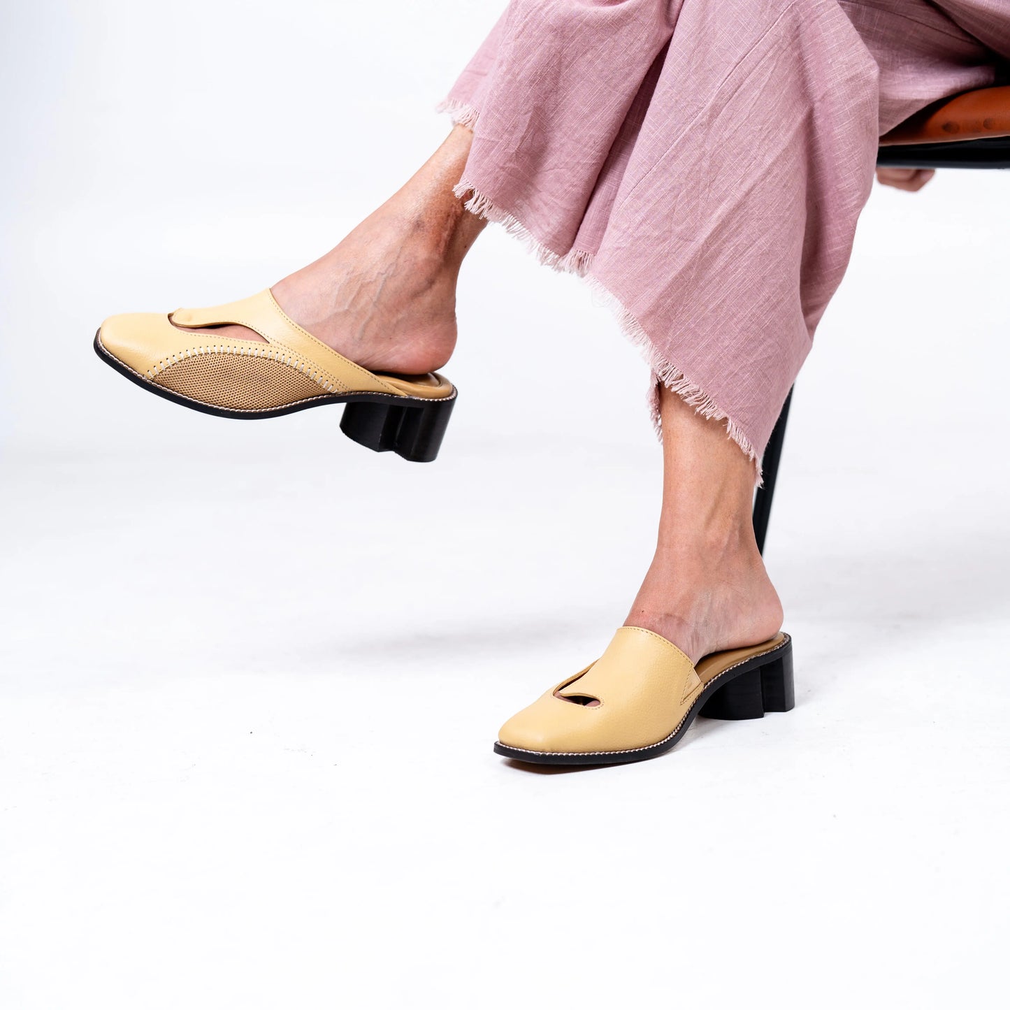 Yellow loafers worn with pink pants on a white background