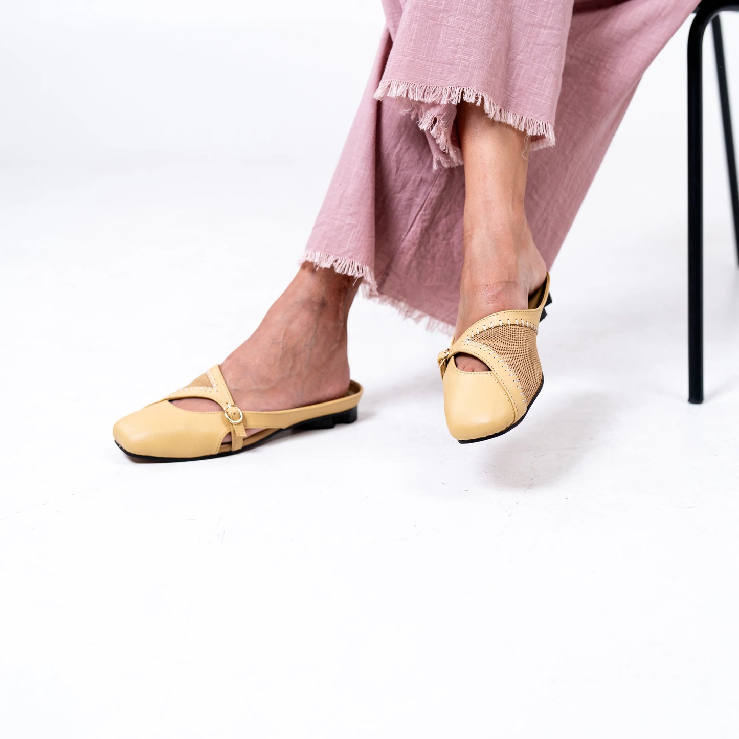 Yellow flats worn with pink pants on a white background