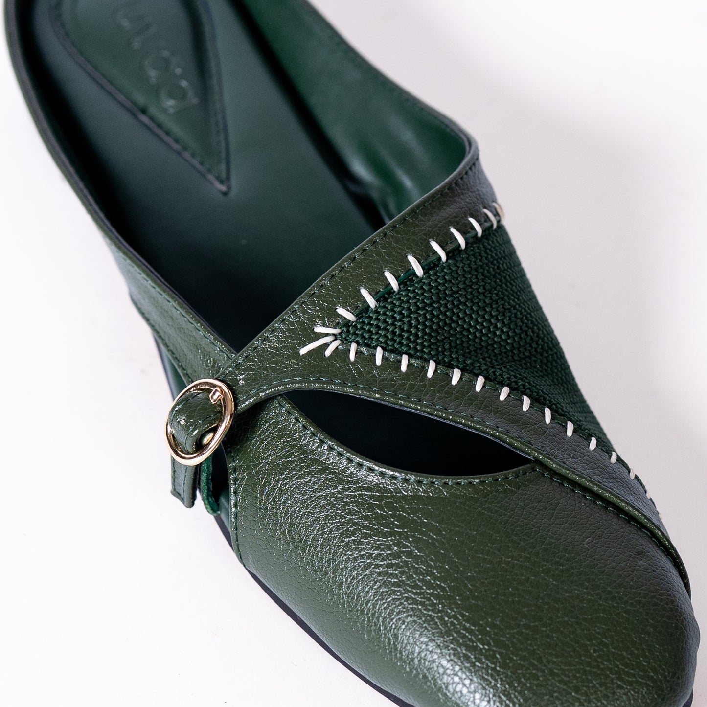 Green shoe with a strap and buckle on a white background