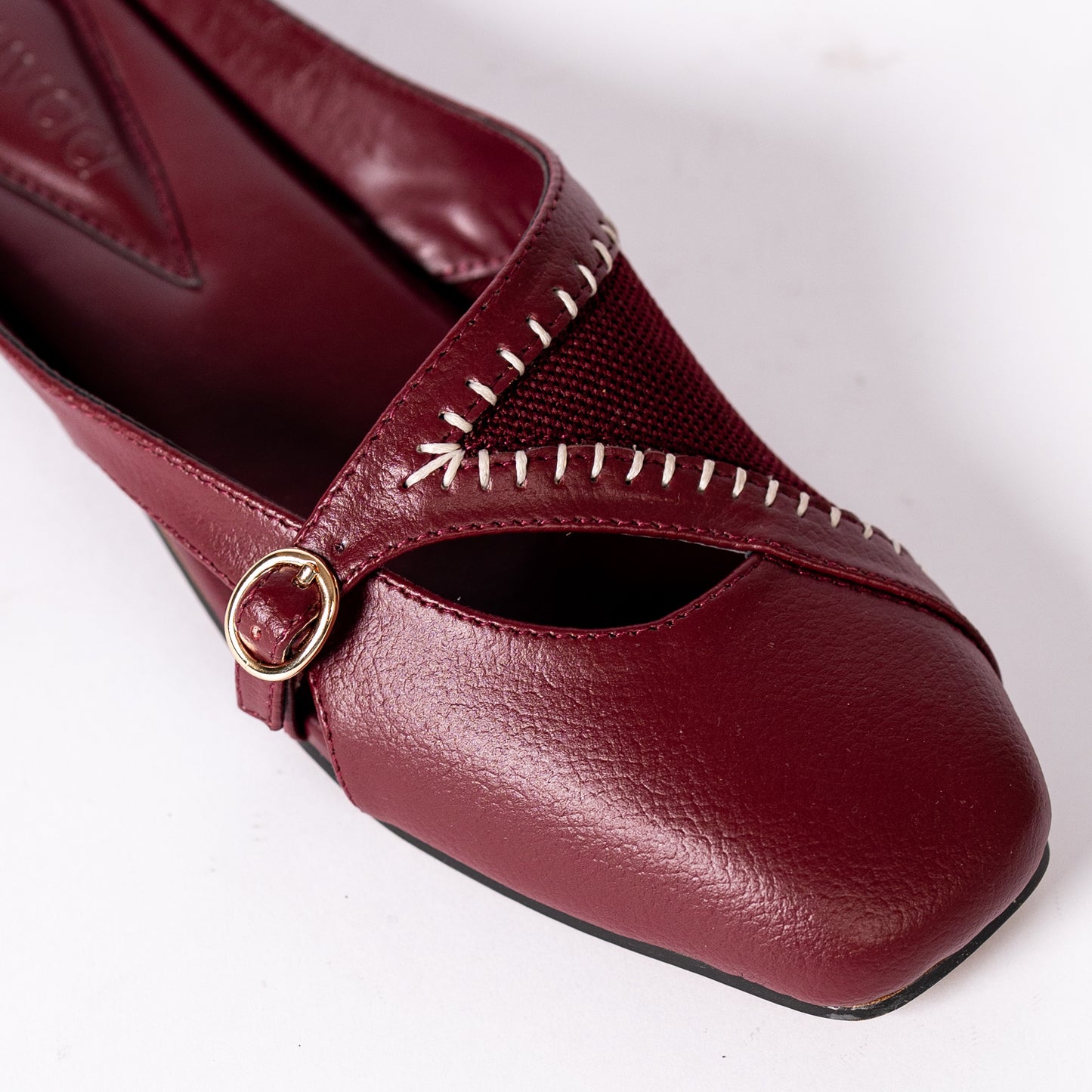 Maroon shoe with gold buckle on a white background.