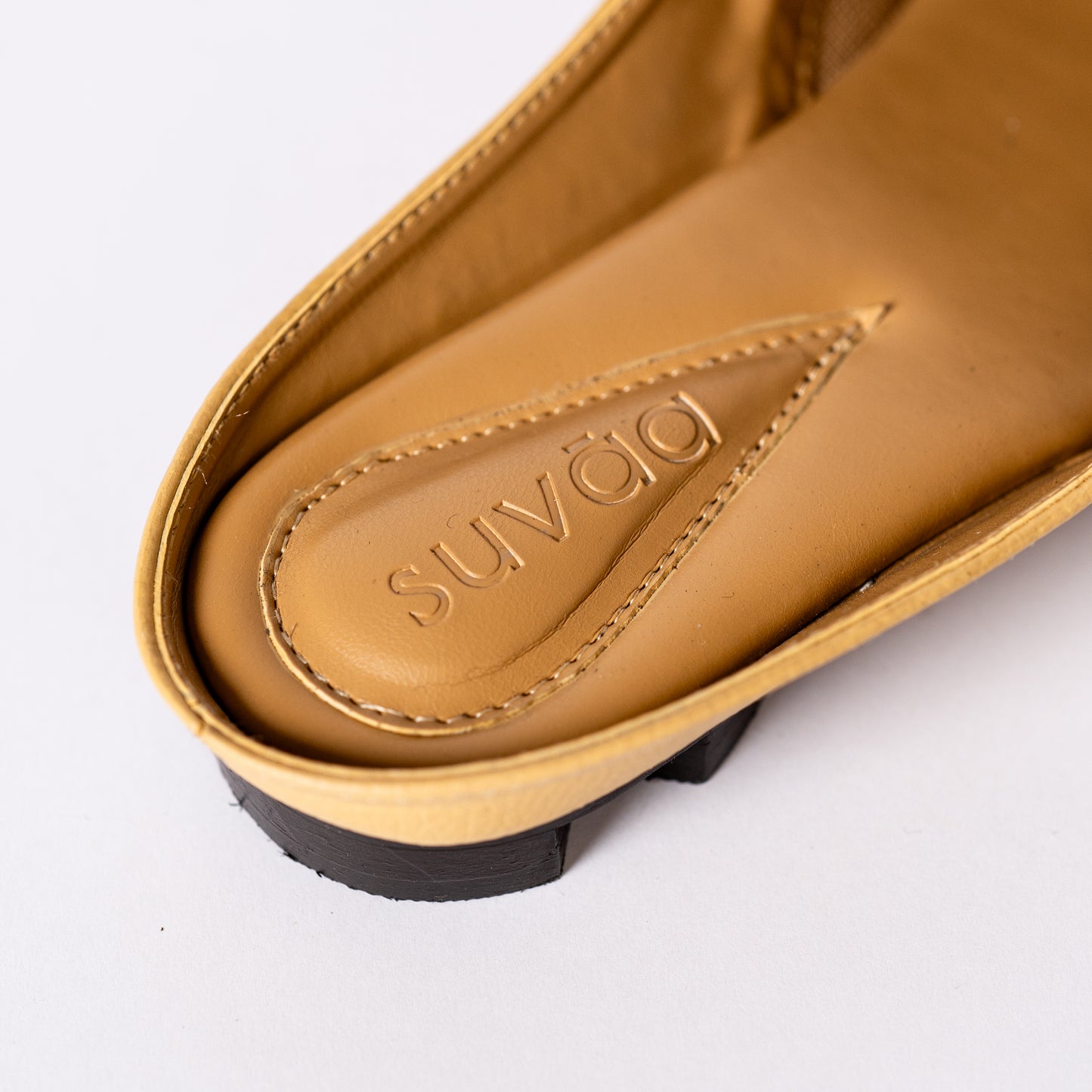 Close-up of a yellow sandal with 'Suvaa' branding on a white background.