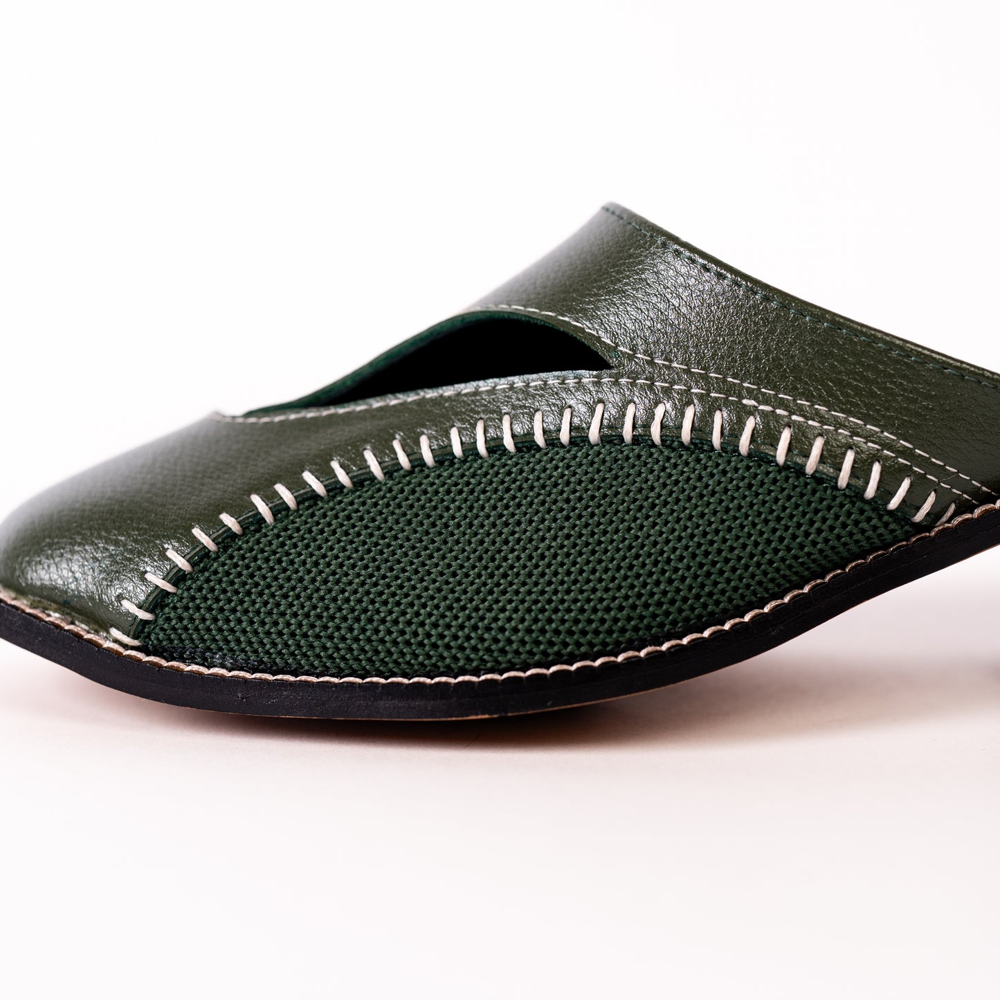 Olive leather mule with visible stitching on a white background
