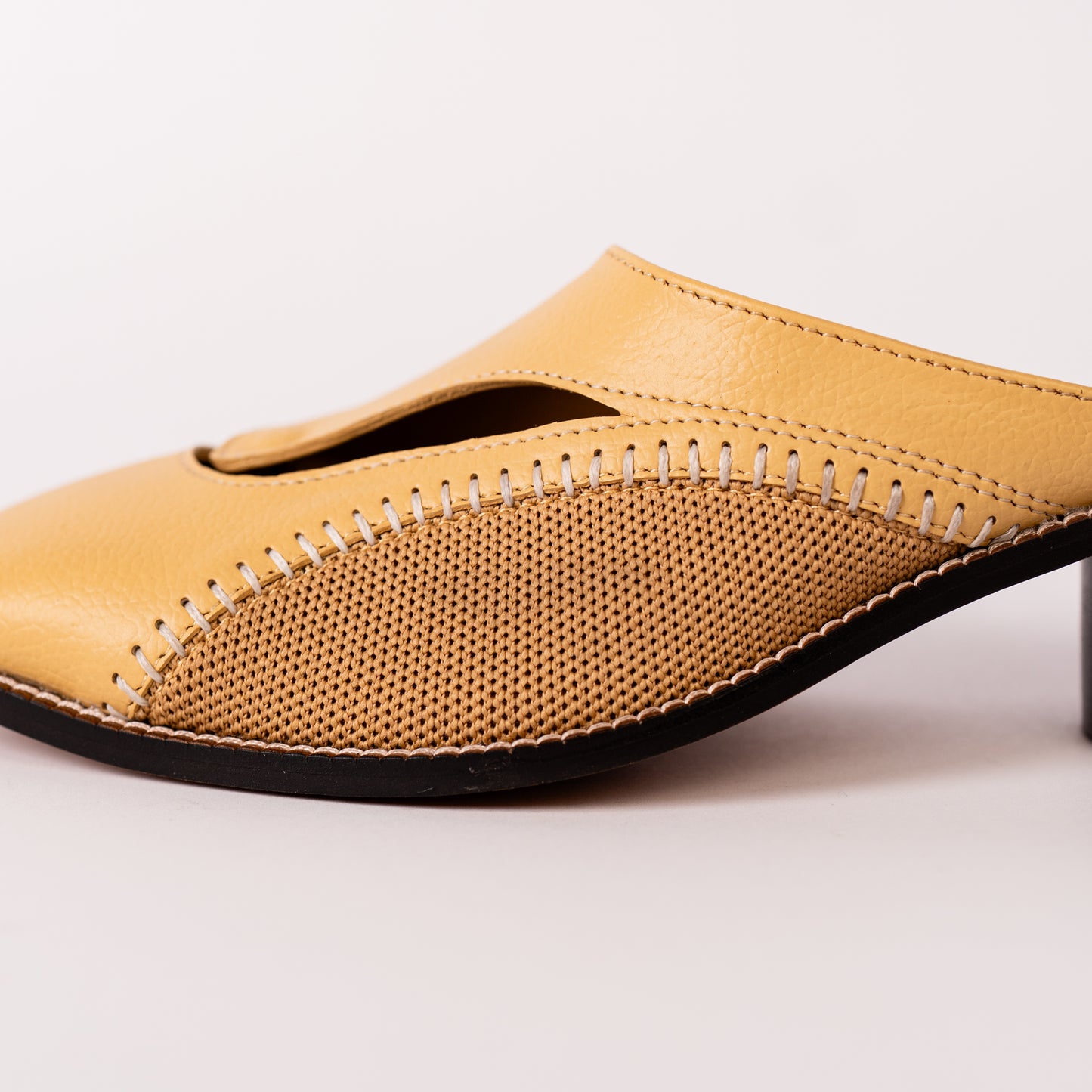 Yellow slip-on shoe with textured surface on a light background.