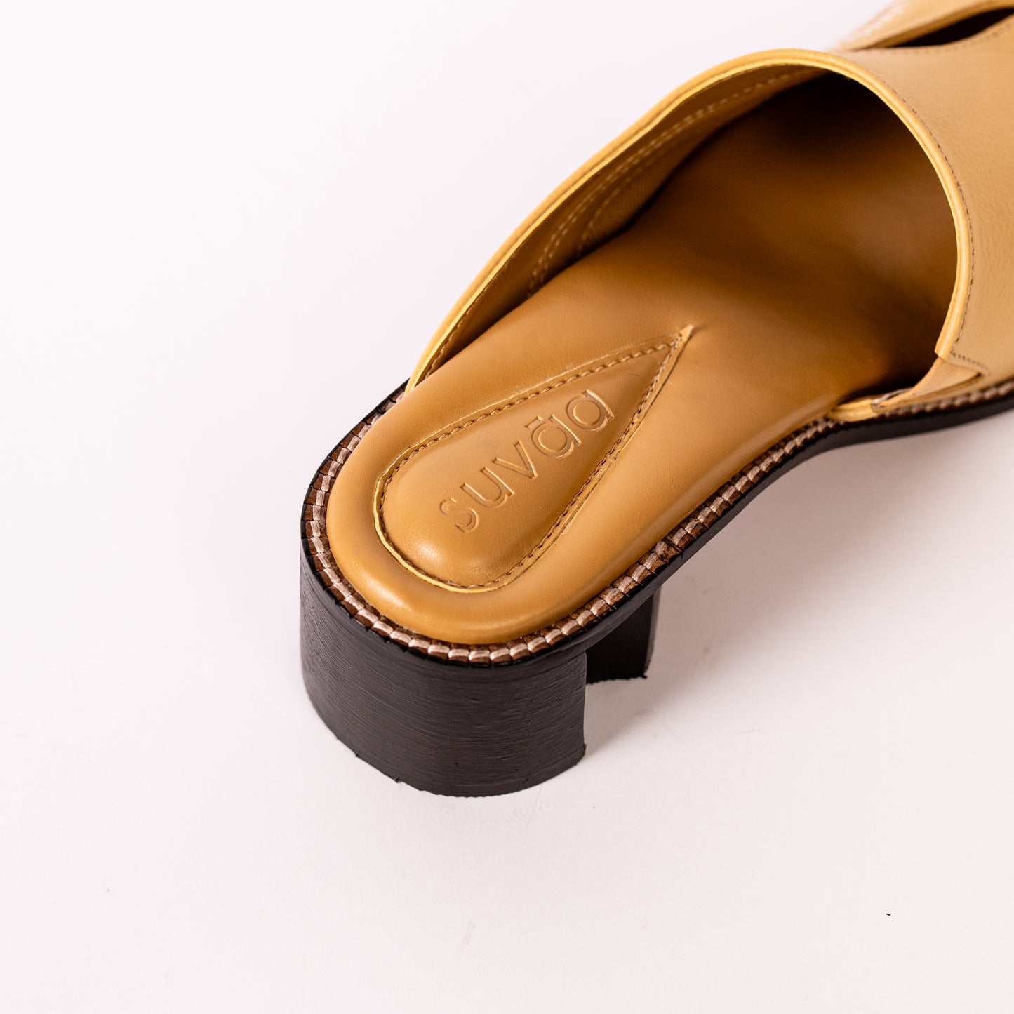 Yellow mules with chestnut brown sole on a white background.